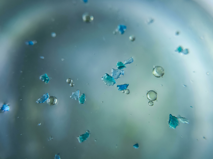 Representación conceptual de bacterias resistentes dispersándose a través de microplásticos en el ambiente